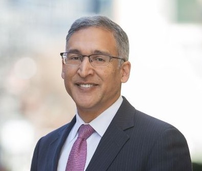 man in blue suit and lilac tie standing in a street