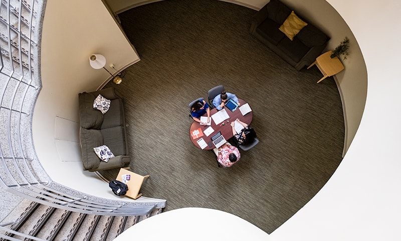 A birds-eye view of people working at a table, surrounded by curved architecture