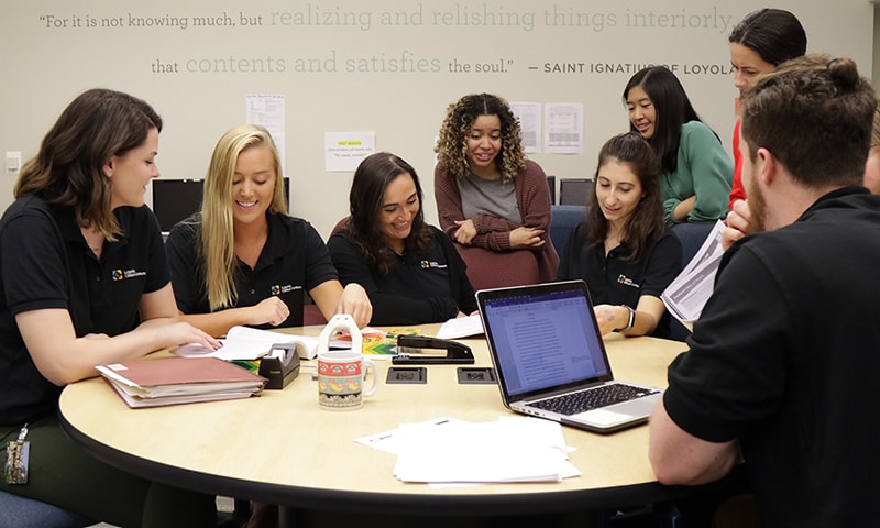 Graduate students sitting and standing around a table