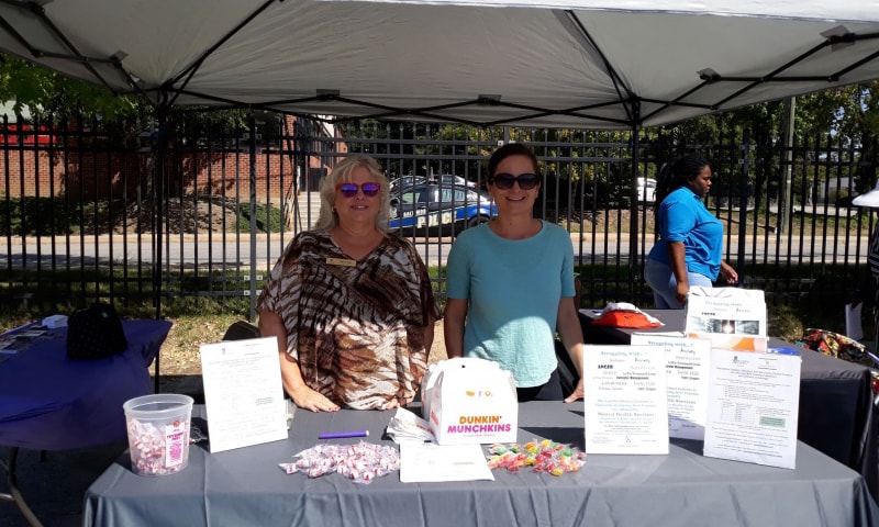 Donna Pitts and Katherine Hadley Cornell standing beneath a tent on a bright and sunny day