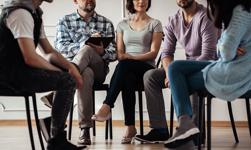 Adults sitting in chairs in a circle having a discussion