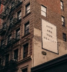 photo of brick apartment building with image on the side of the building How Are You Really