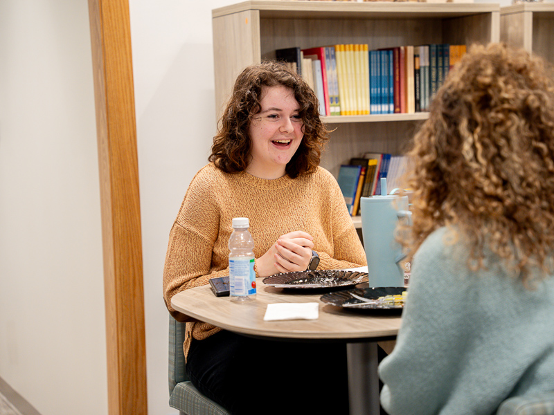 a woman laughing while conversing with another person