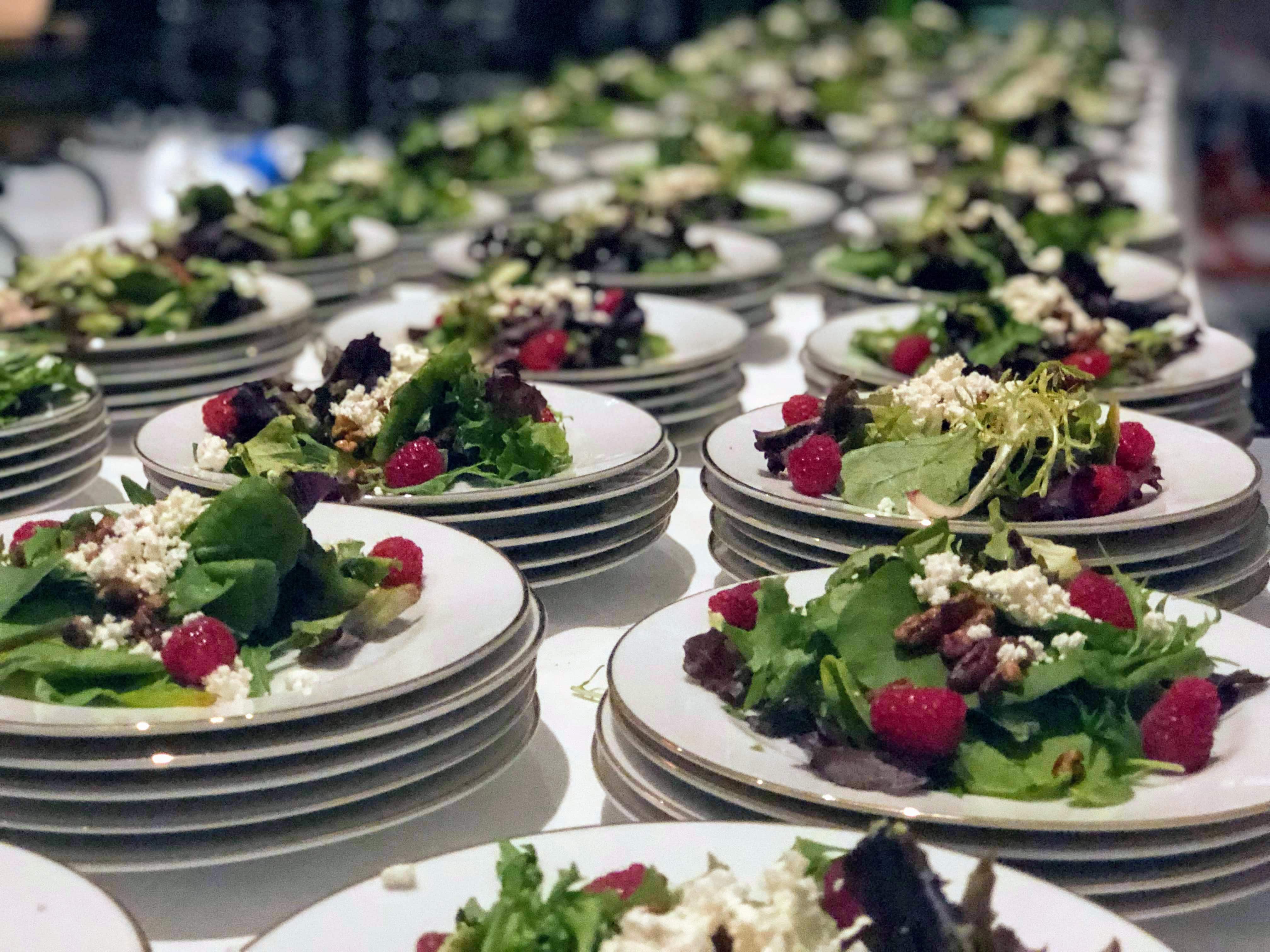 plated salads with fresh greens, cheese, and nuts line a table