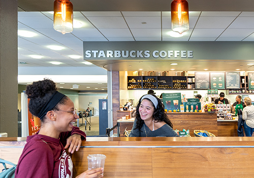 Students smiling in front of Starbucks