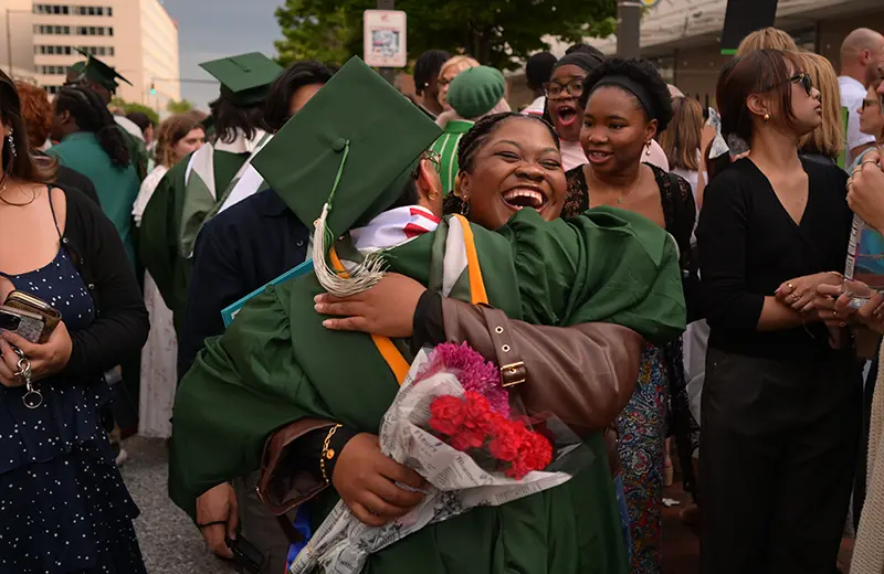 Loyola graduate and his mother squeeze each other in a tight hug with huge smiles as other students greet their parents after graduation