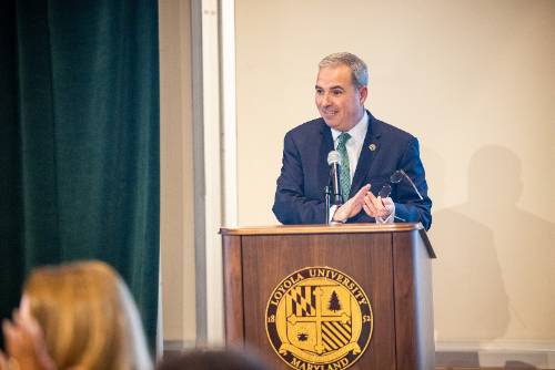 Man standing at podium smiling and clapping.