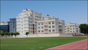 A photo of a building-The American University of Dubai, a white building in front of a field.