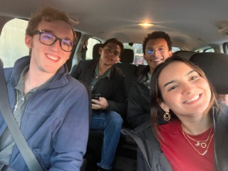 A group of four people smiling while taking a photo in the car