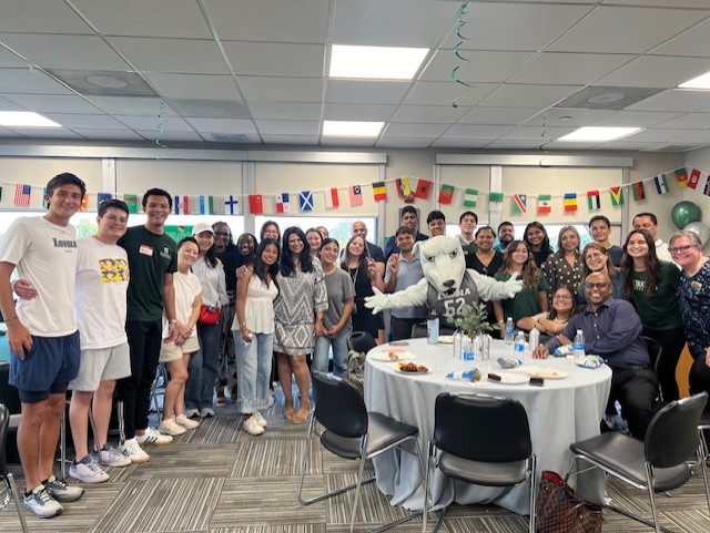 A group of people celebrating at a gathering with world flags hanging around the room