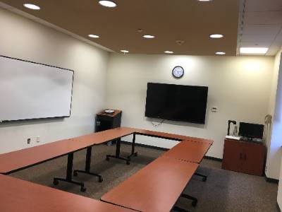 Tables arranged in rectangle, large television, whiteboard