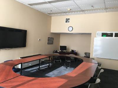 tables arranged in oval, large television, whiteboard