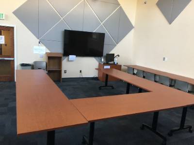 Desks arranged in horseshoe shape, large television