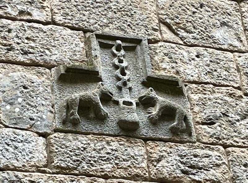 Crest of Loyola family on stone wall, showing two wolves and a cooking pot