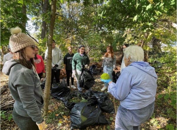 Student cleaning up waste in a wooded area