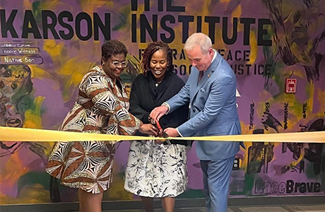 Terry Sawyer, Cheryl Moore-Thomas, and Kaye Whitehead cut yellow tape in front of Karson Institute wall art