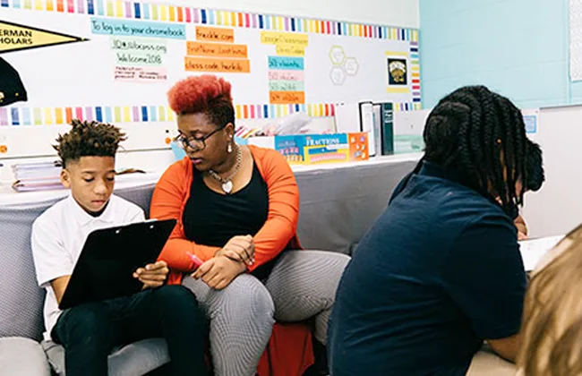 An adult works with students in a classroom