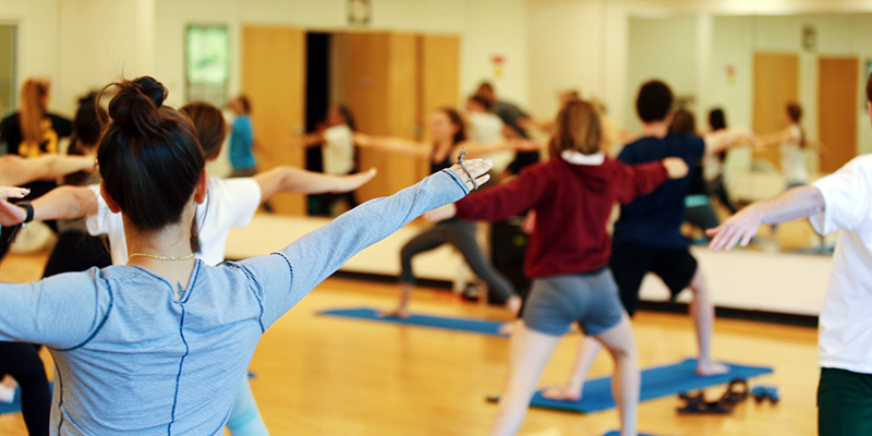 Loyola community members with arms outstretched in yoga a yoga pose during a group fitness class