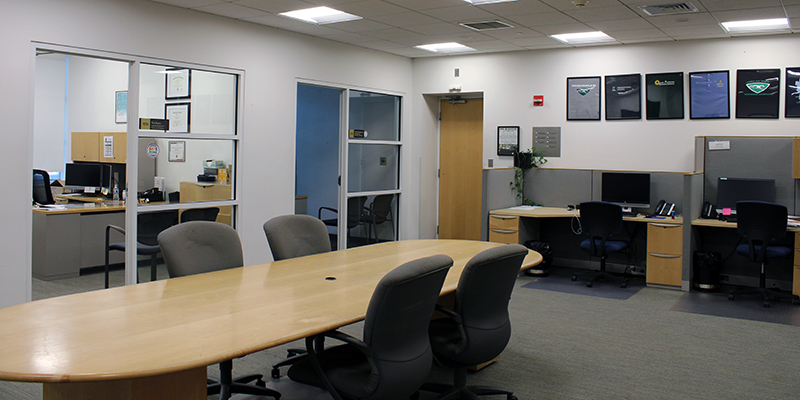 A large room with conference table and chairs, along with various offices connecting off of the main room