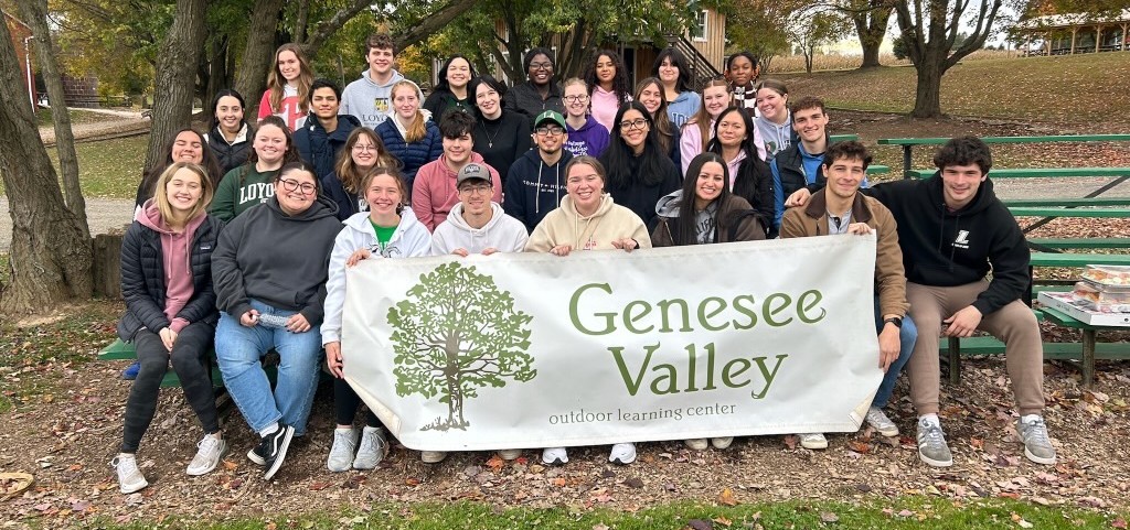 A group of students smiling holding a Genesee Valley sign