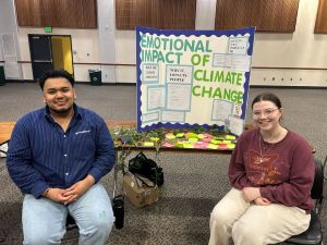 Two Students in front of Psych of Climate Change class poster