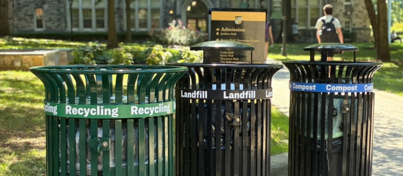 Waste receptacles on campus with color coded stripes for recycling, landfill, and compostable content