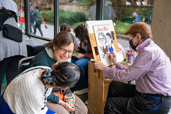 Student and parent sit for caricature drawing