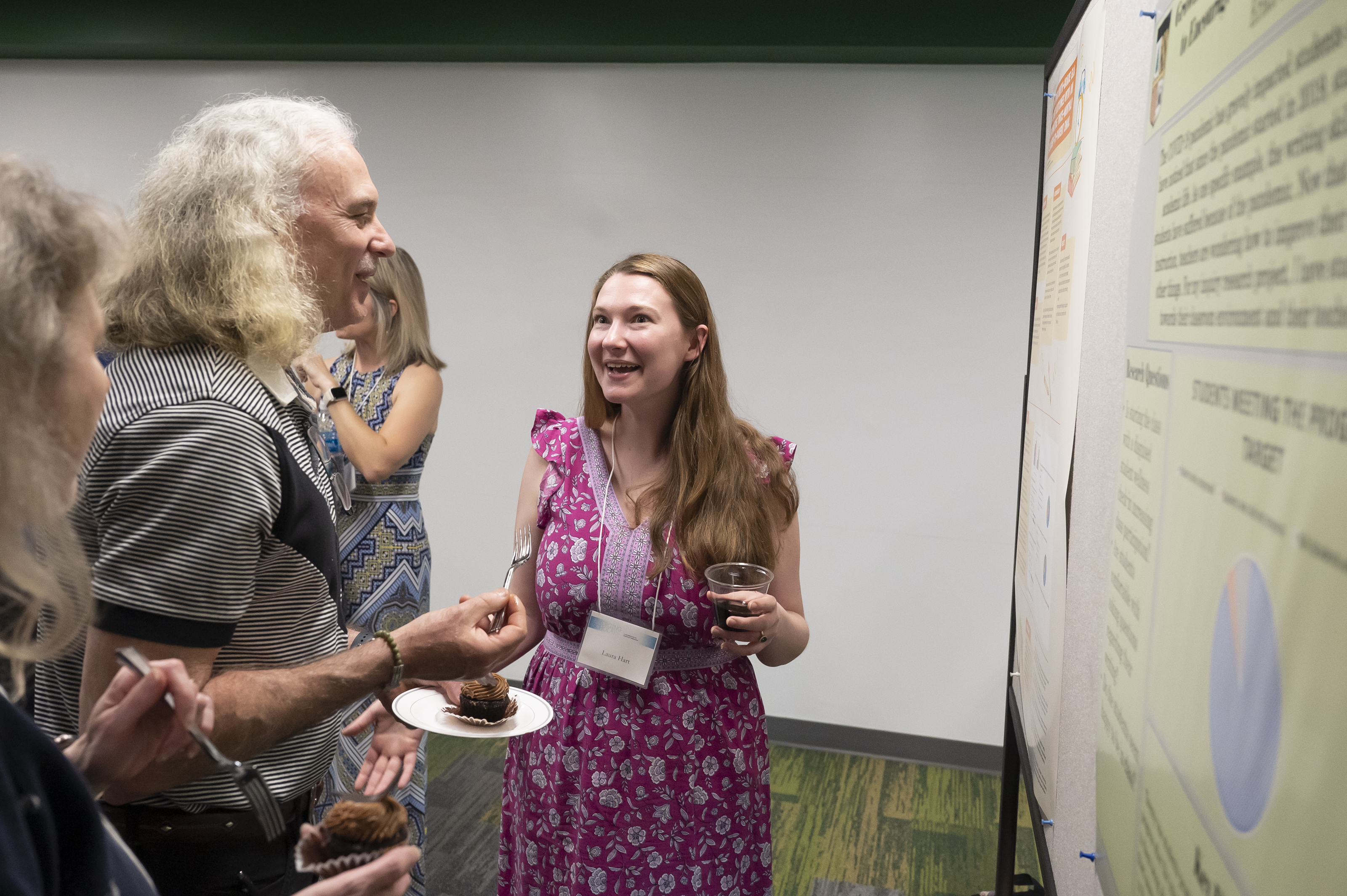 Graduate student smiling in front of research poster