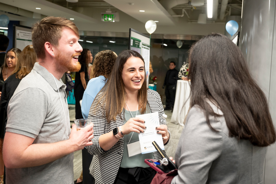 Group of three graduate students smling and conversing at Emerging Scholars 2024