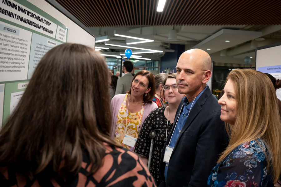 Presenter discusses research findings with group of visitors at Emerging Scholars program at Loyola University Maryland