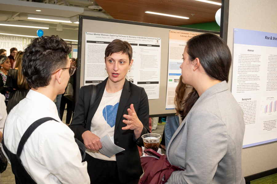 Graduate students in discussion in front of poster at Emerging Scholars Loyola University
