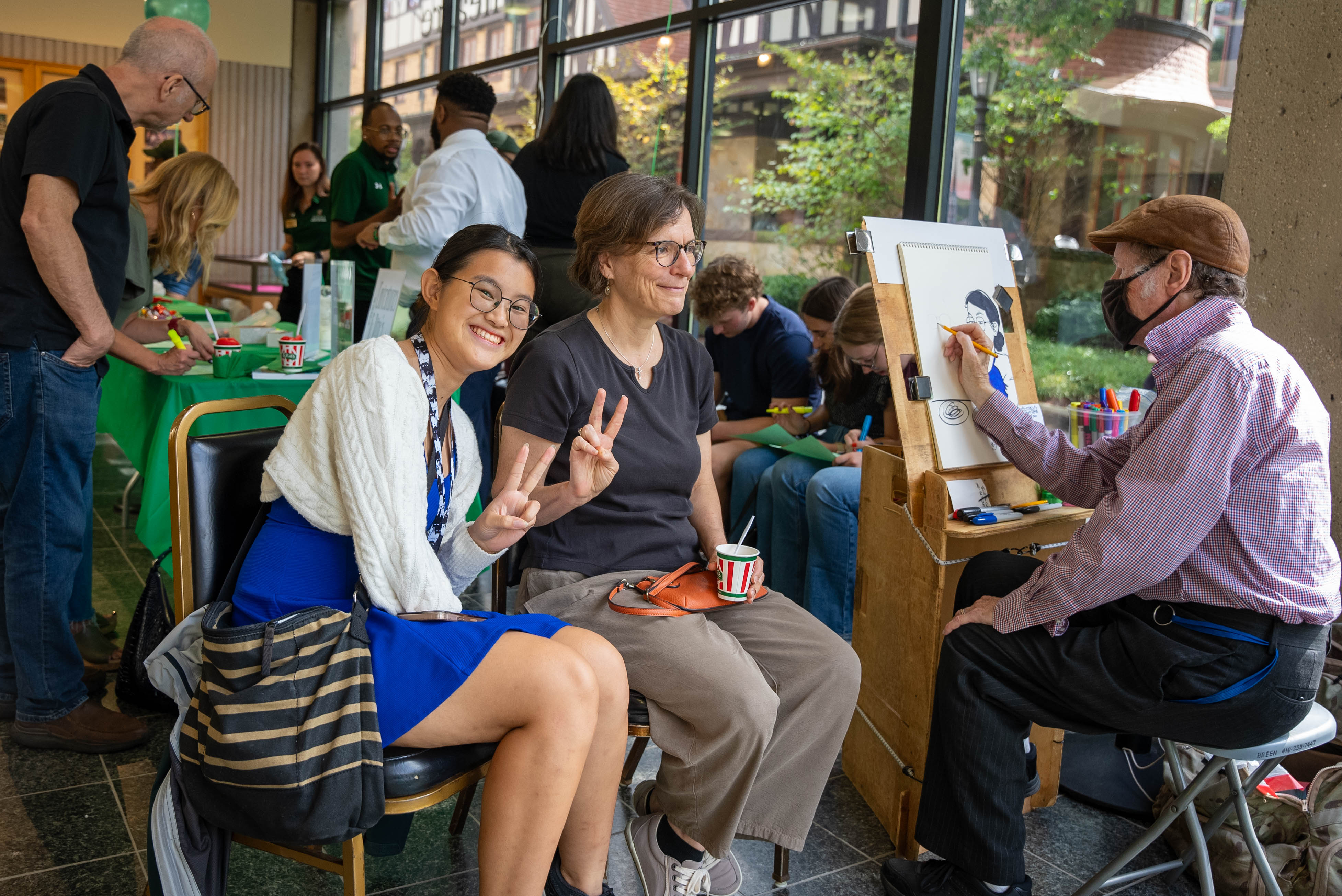 A mother and daughter pose for a caricature painting
