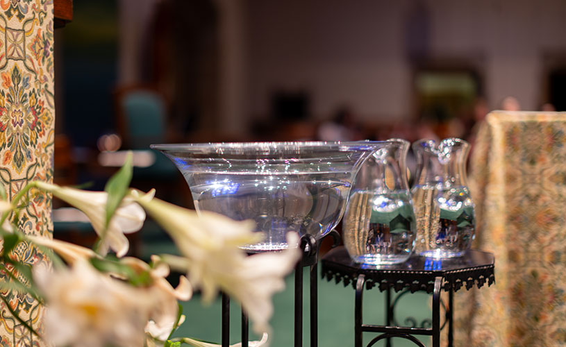 Glasses of holy water in the foreground with a blurred background of the mass