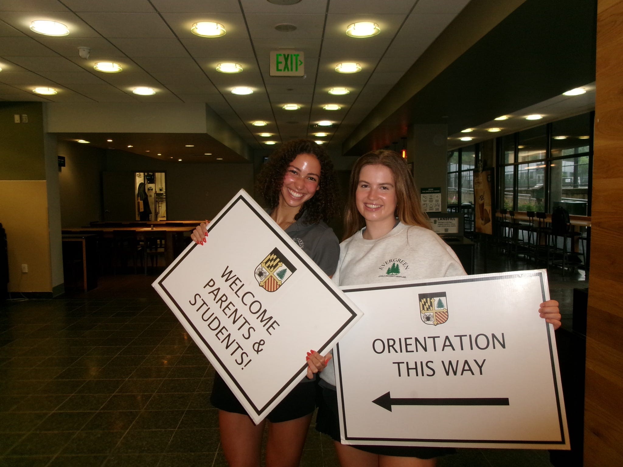 Two students holding signs leading to orientation