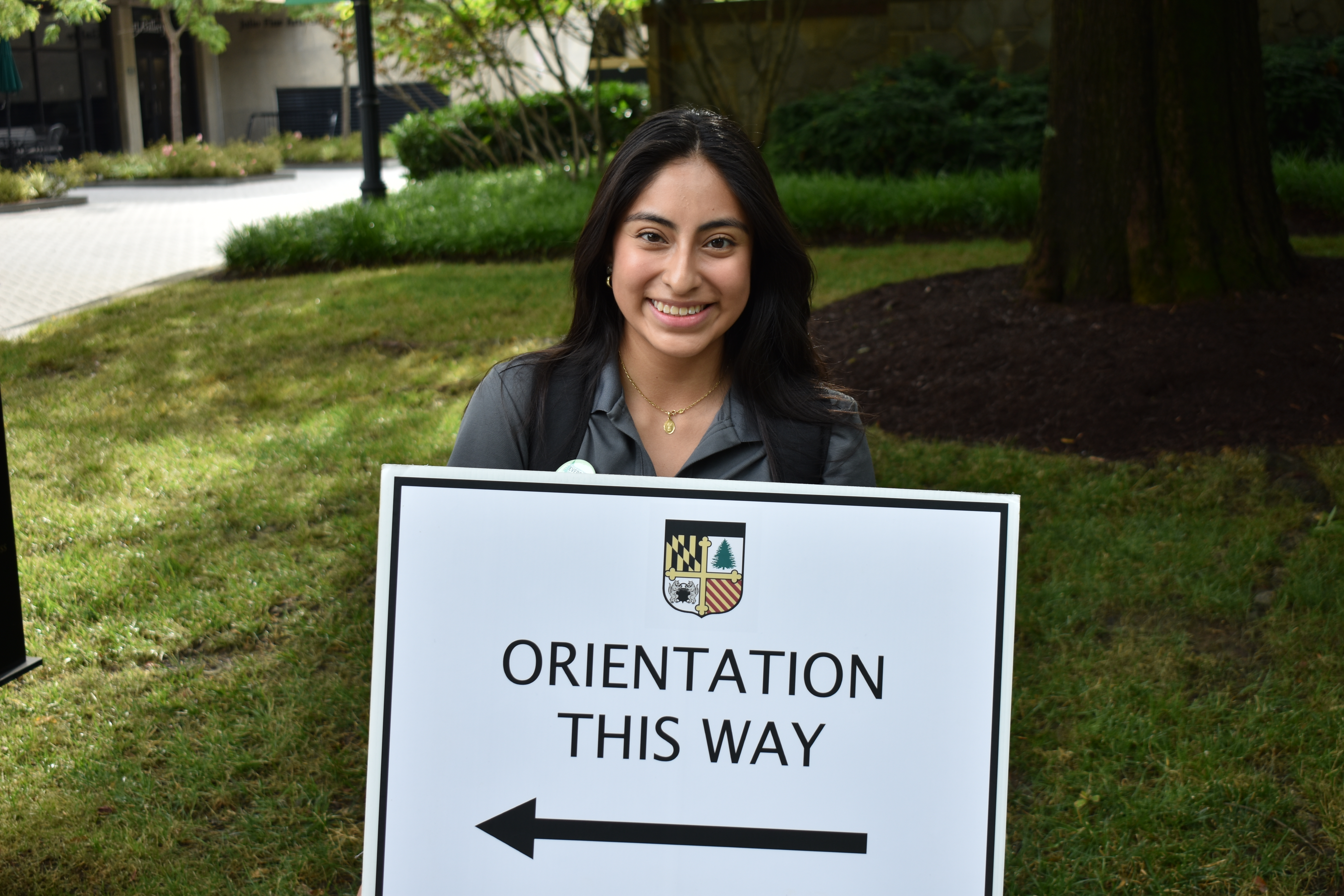 Loyola Student holding an orientation this way sign