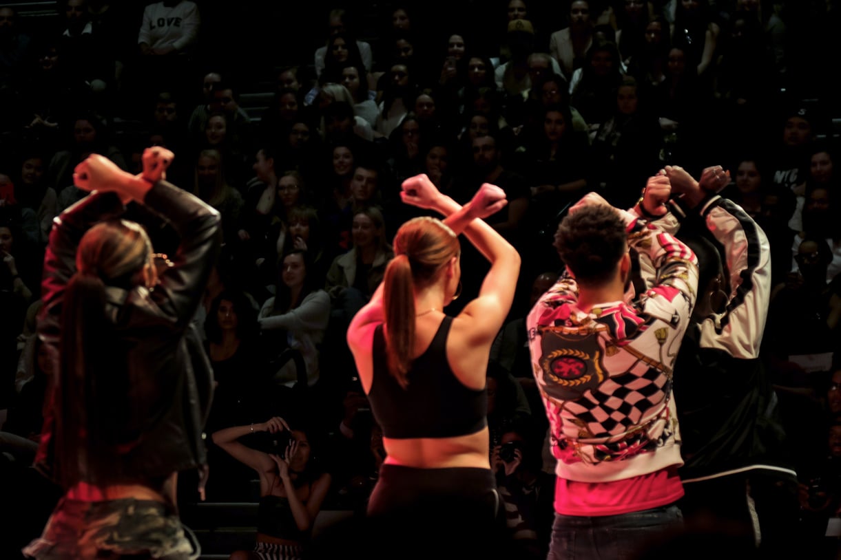 Student models pose in front of a crowd during a fashion show