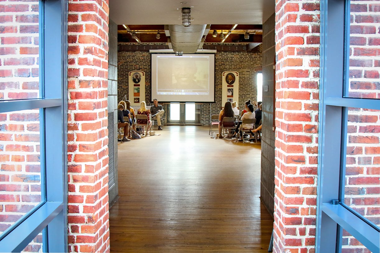 A class sits inside of a brick business building, seen from behind looking through the doorframe