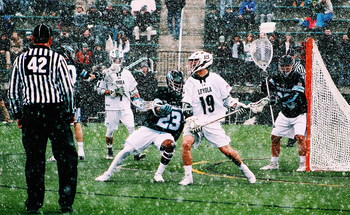 Loyola lacrosse players playing against Hopkins during a snowstorm