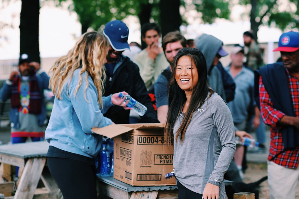 A student smiles for the camera while handing out water bottles to the homeless and hungry in Baltimore