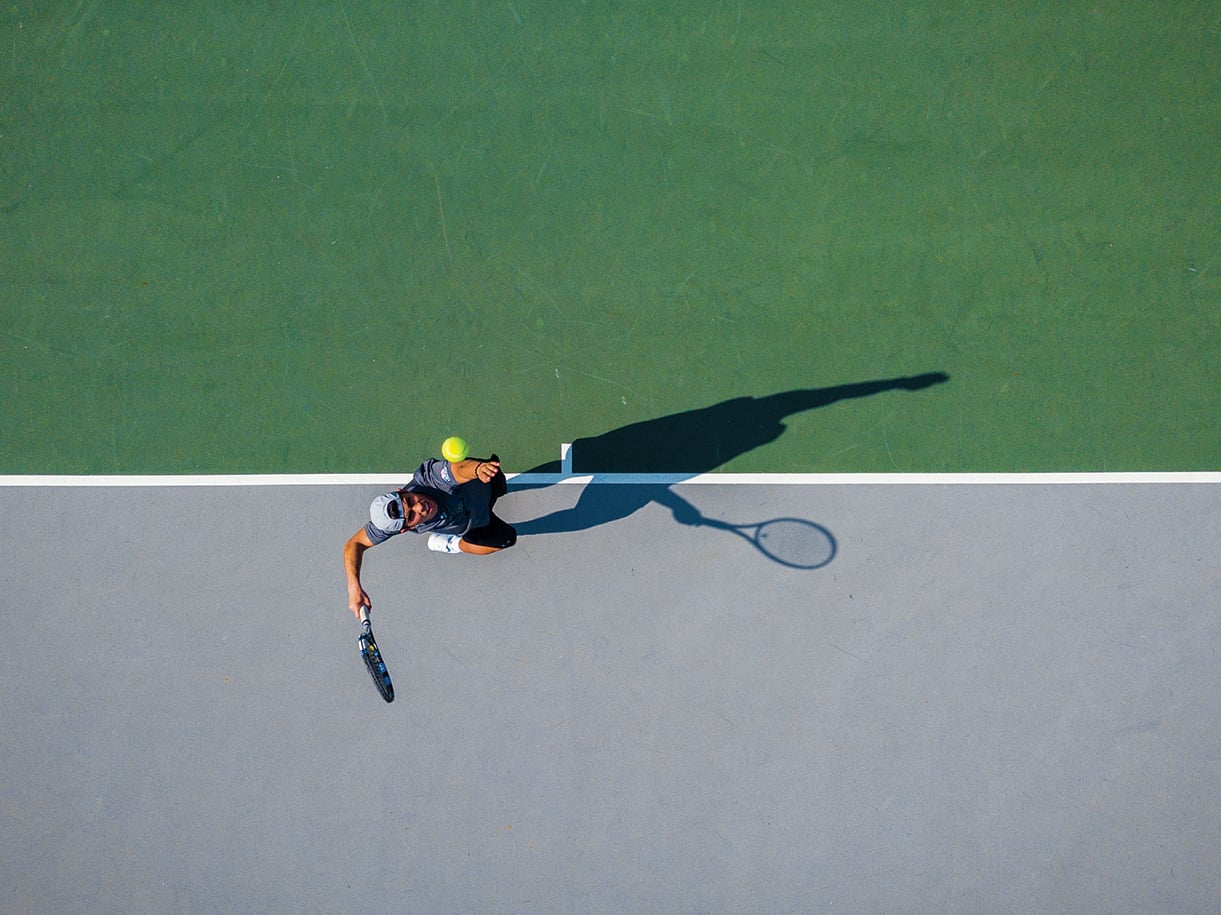 A birds-eye view of a player serving on a tennis court