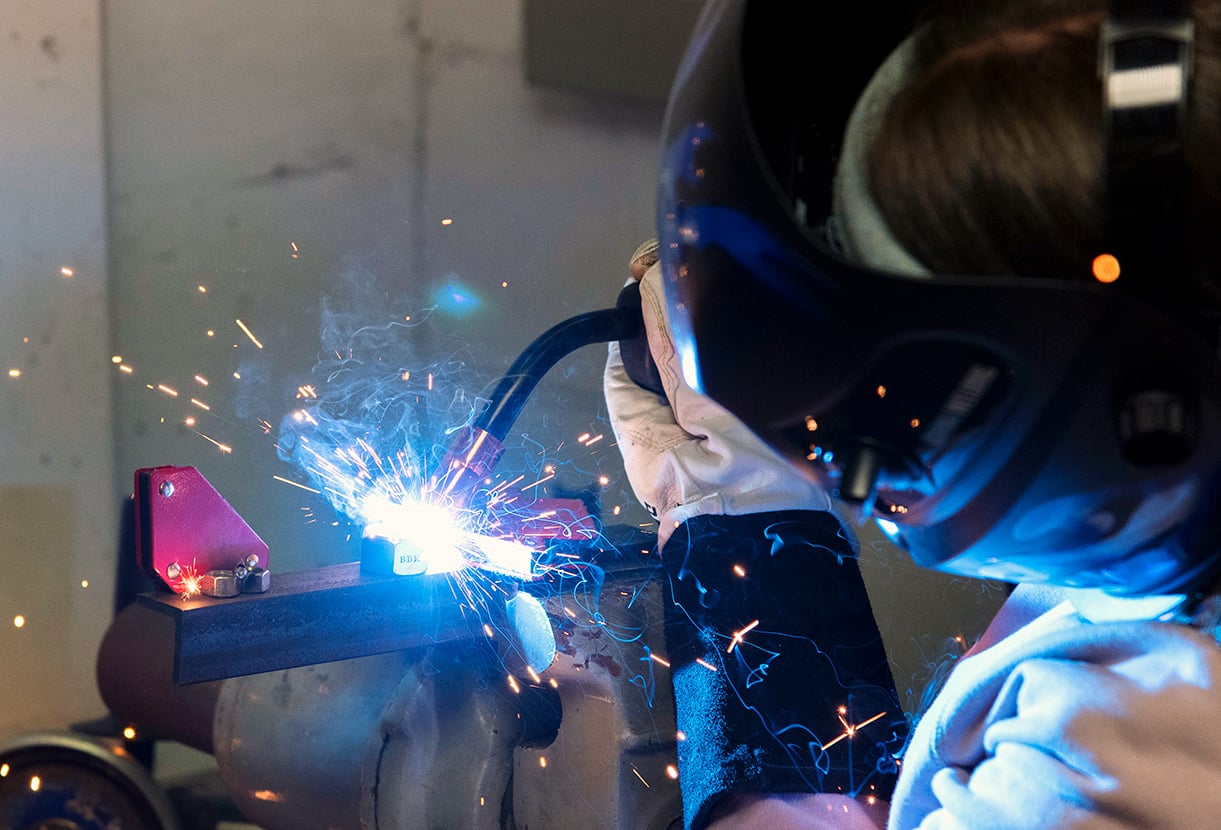 A student welding, with bright sparks flying everywhere