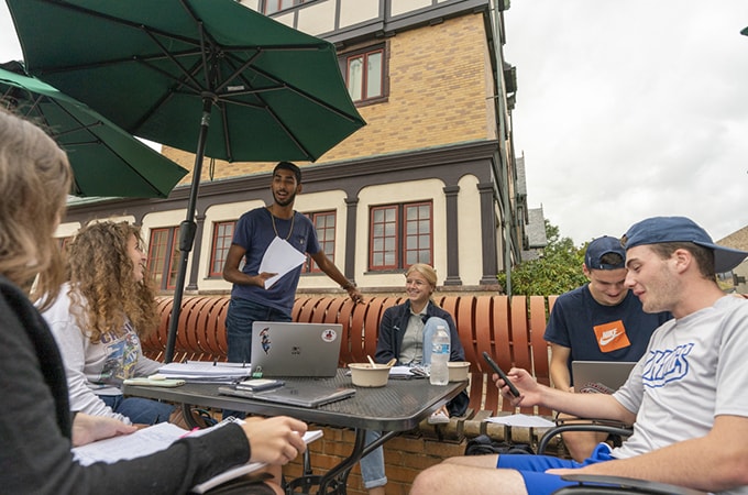 A group of students sitting together on the benches near the Knott Humanities Center