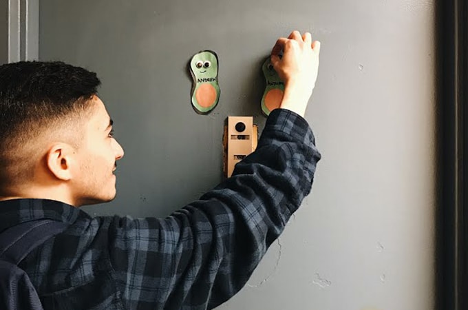 A resident assistant hangs decorations on the exterior of a door of a dorm