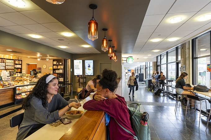 Two students conversing and eating at one of the on-campus Starbucks