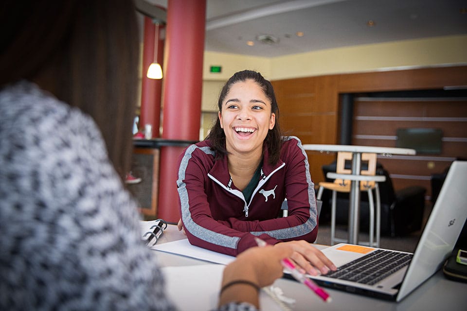 Two students talking with each other next to a laptop