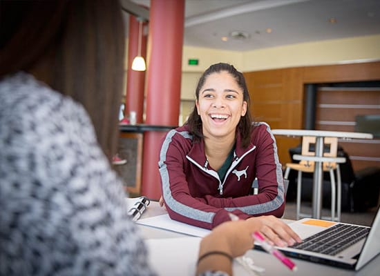 Two students talking with eachother next to a laptop