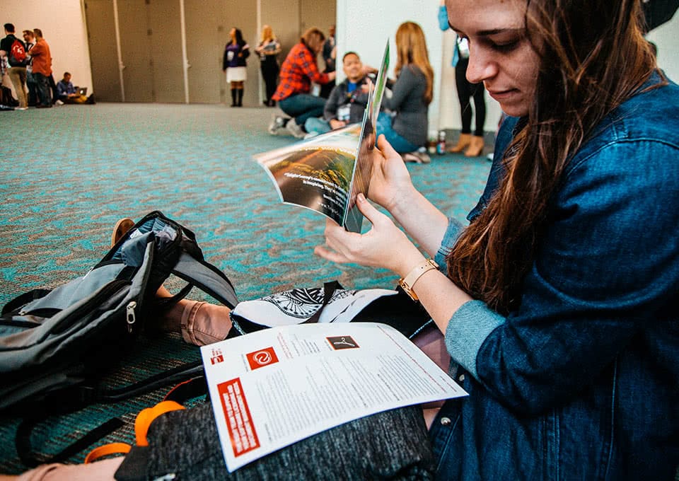 Student sitting on the floor looking through conference materials