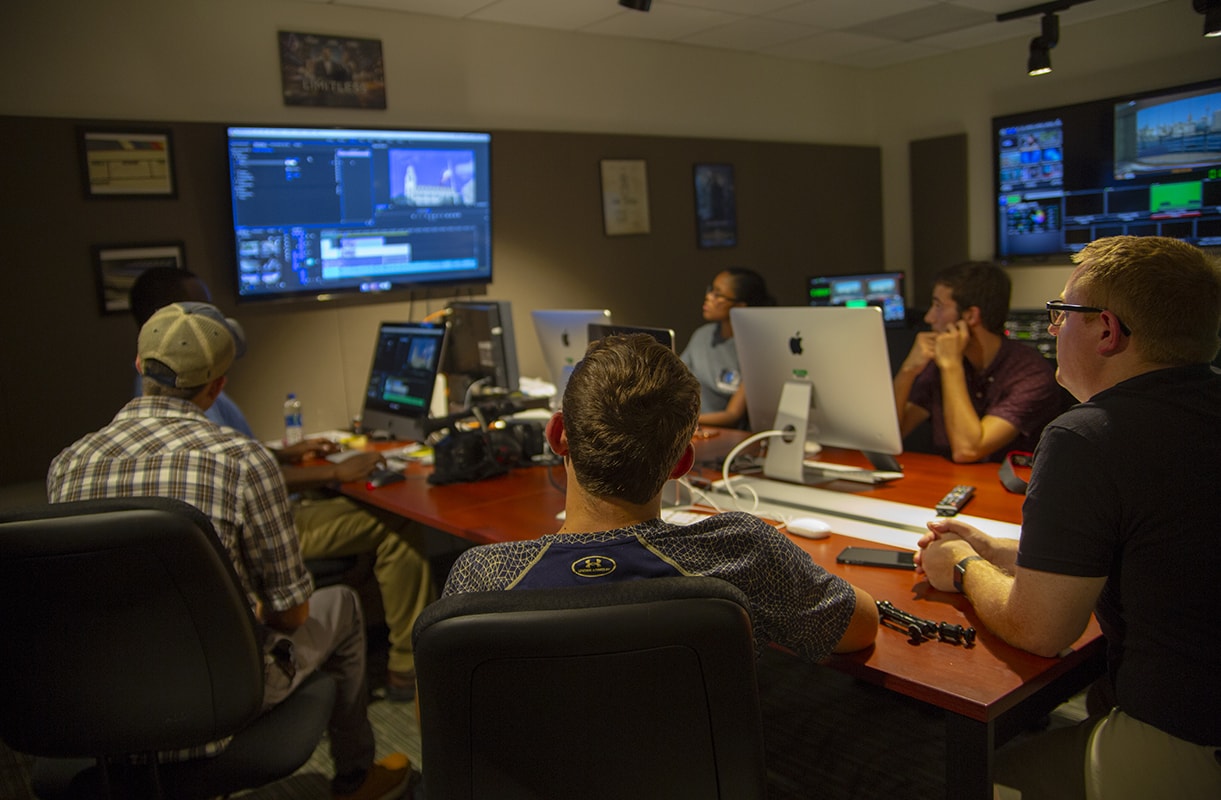 Group of students looking at video editing software on a TV