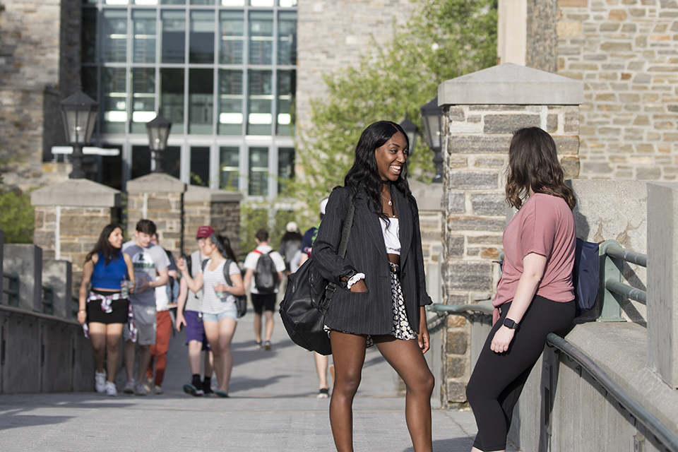 Two students stopping to chat on the pedestrian bridge on a sunny day