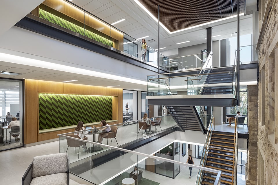 Interior of a clean, modern building with students studying at various tables next to a stairwell